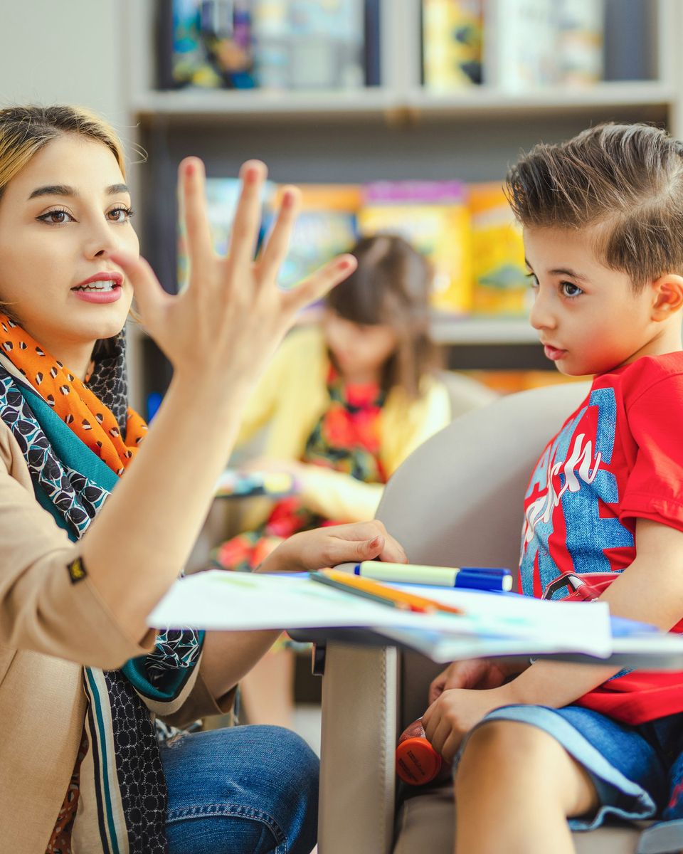 A teacher working with a young boy at a classroom table