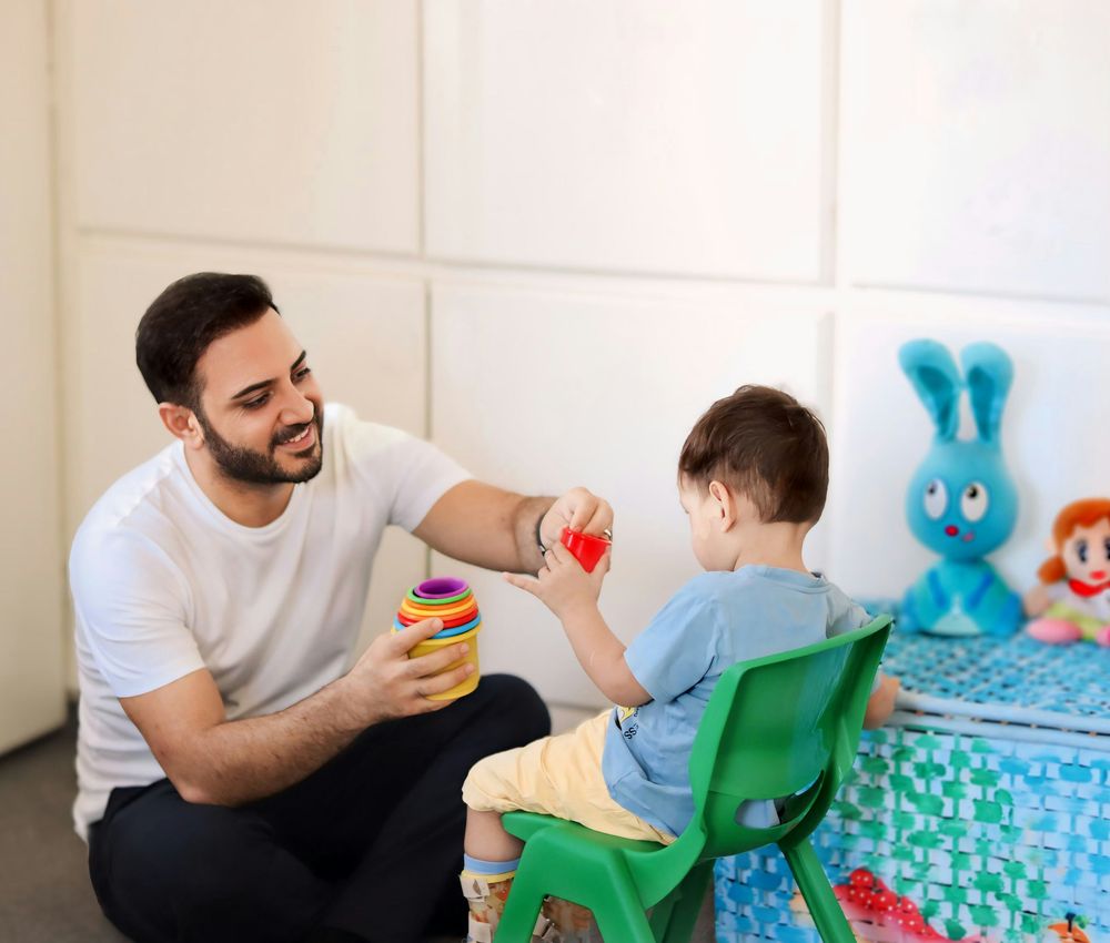 A therapist playing with a young boy using colorful toys
